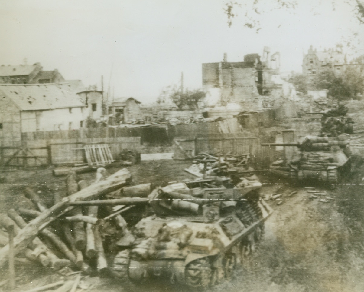U.S. Tanks Roll into Aachen, 10/14/1944. GERMANY – Guns pointed toward enemy positions American tanks roll deeper into Aachen past bomb-gutted buildings.Credit (Army Radiotelephoto from Acme);