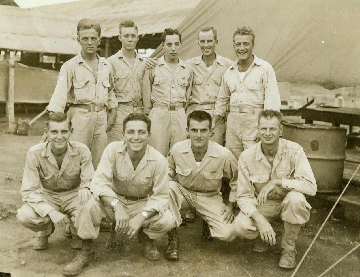 Paratroop Cooks And Waiters, 10/18/1944. South Pacific – Nine Yank paratroopers, who serve as cooks and waiters for an airborne unit, pose for their photo outside the mess tent. Left to right: (Front Row) Pfc. John Gurriell, Paterson, N.J.; Pfc. Joe Baldino, Philadelphia, Pa.; Pvt. Billy J. Rudolph, Paducah, Ky.; Pvt. Harold Richardson, Oakland Calif.; (Back Row) Pvt. Emil Decola, Philadelphia Pa.; Pvt. Weldon Cooper, Roscoe Texas; Pvy. Ernest Apodach, Phoenix, Ariz; Pfc. Maurice Dalton, Pawtucket, R.I.; and Pfc. Michael Simolo, Brooklyn, N.Y.  10/18/44 Credit Line –Wp—(ACME);