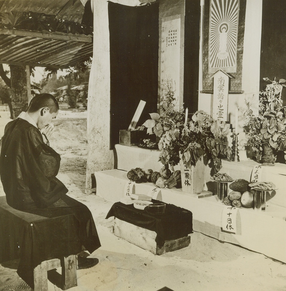 Civilian Life on Saipan, 10/27/1944. Saipan, Marianas – One of the things which Japanese civilians, Kanakas, Koreans, and Chamorro natives of Saipan enjoy under American occupation is freedom of worship.  Here Hideki, the Buddhist Priest, prays before an altar decorated with flowers and food.  “Shintoism,”or emperor worship, has proved a problem in religious freedom – US authorities have made no attempt to stop it, but have set up no facilities to encourage it.;