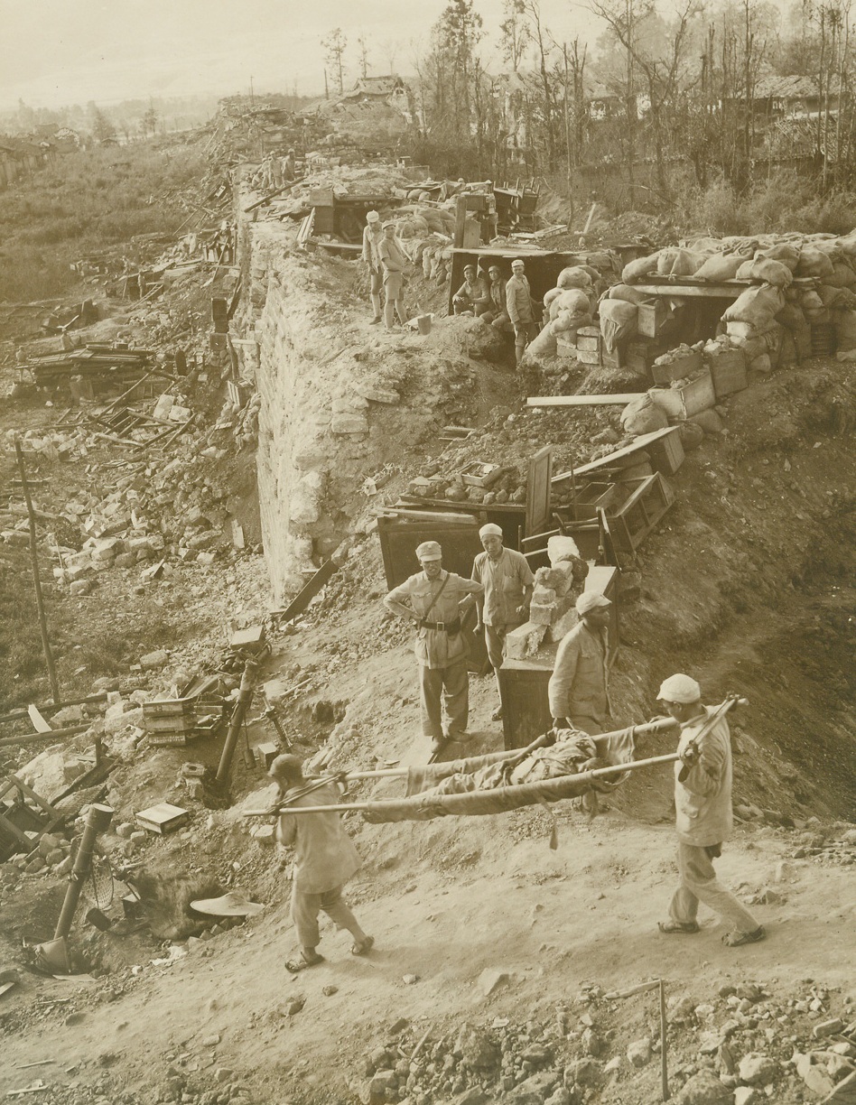 The Bloody Siege of Tengchung, 10/4/1944. Tengchung, China – Inching across the rugged, rain-soaked terrain of the Kaoli mountains to face a heavily-fortified Jap force at Tengchung, American-trained Chinese tropps captured the ancient Jade center after a bloody, five-week battle.  The first Chinese city was the Eastern side of Burma to be liberated by the allies, Tengchung was a battle-seared, bubble-strewn prize then the Chinese moved in.  Approximately 2000 Japs, who were entrenched for a six-month siege, were killed or captured in the battle, which proved the Chinese Army’s ability to use modern weapons and tactics.  The U.S. 10th and 14th Air Forces supported China’s fighters in the siege of the principal enemy obstacle to the junction of the Ledo and Burma roads.New York BureauWounded Chinese are carried past an allied position on the city’s massive stone walls.  The wall was already captured, but fighting raged within Tengchung when this photo was made by Frank Cancellare, ACME photographer for the War Picture Pool.Credit Line--WP--(ACME);