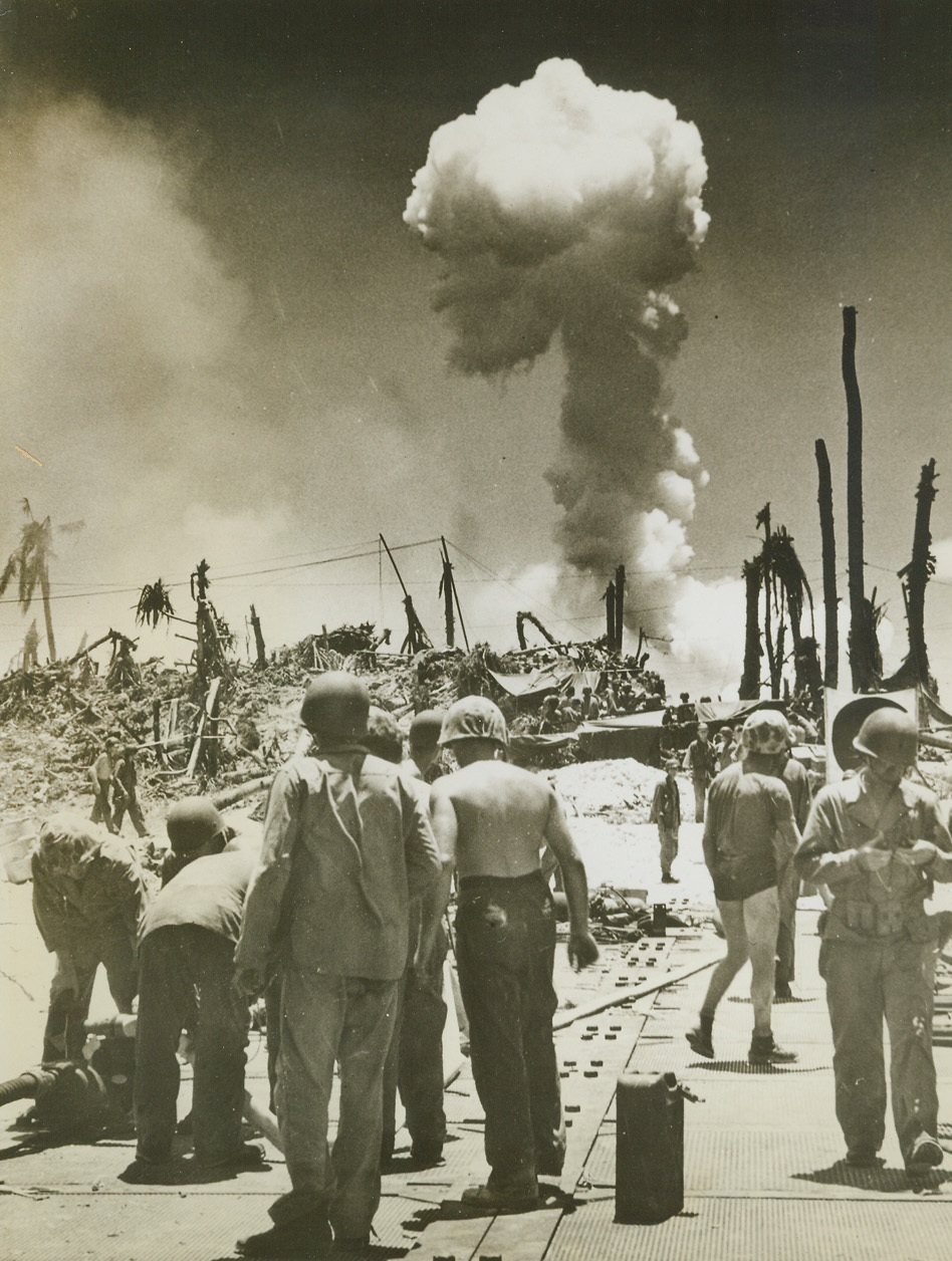 Ammo Dump Burns Sky High, 10/6/1944. Pacific – Coast Guardsmen and Yank troops hastily rig a hose to combat the blaze caused by a burning ammunition dump near the beach on Angaur Island.  Island, located six miles to the South of Peleliu, fell to American invaders recently after fierce Jap resistance was beaten back.Credit (Coast Guard photo from ACME);