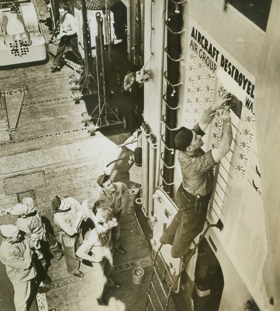 No Title. 10/14/1944. At Sea – A group of sailors watch intently as a crew member posts the score of Jap planes destroyed after the first U.S. carrier sweep against Manila, capital city of the Philippines. Credit-WP-(ACME);