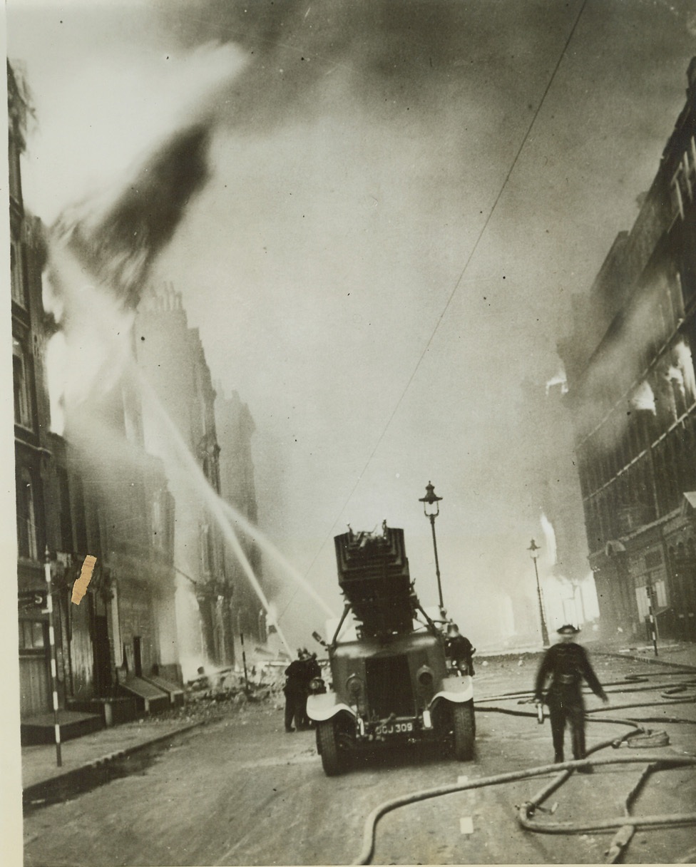 When London Burned in 1941, 10/19/1944. Fire-fighters strive desperately to beat back flames shooting from buildings along Queen Victoria Street in London during the Nazi blitz in 1941. The international headquarters of the Salvation Army is at right. This photo depicting the ferociousness of the '41 blitz has just been released by the censors for publication. Credit: (ACME);