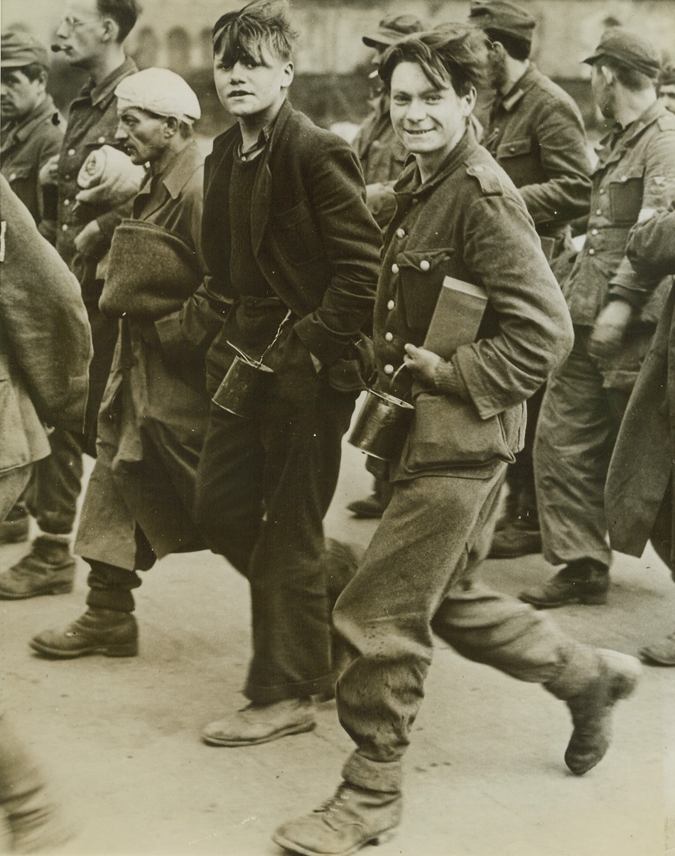 Youngsters Found With Captured Nazis, 10/18/1944. England – Two school-age youngsters march with veteran Nazi soldiers as they head for prison camps in England after crossing the Channel in a landing craft. The youths were taken at Calais. Credit: ACME;