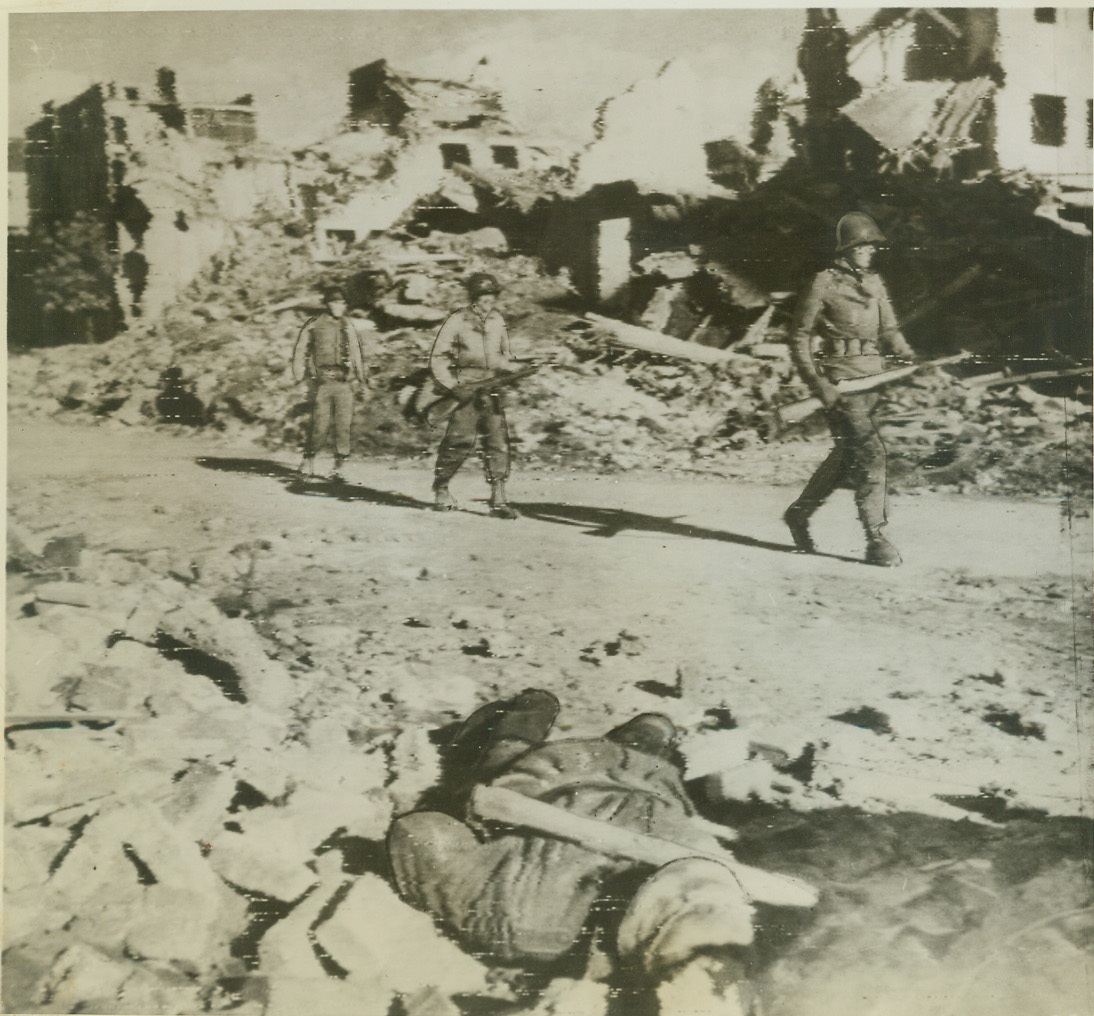Yank Infantrymen Advance Thru Aachen, 10/16/1944. AACHEN, GERMANY – A dead German lies in foreground as American Infantrymen push ahead through the ruined streets toward the center of embattled Aachen. Photo by Bert Brandt, Acme photographer for the War Picture Pool. Credit: (ACME Photo via Army Radiotelephoto);
