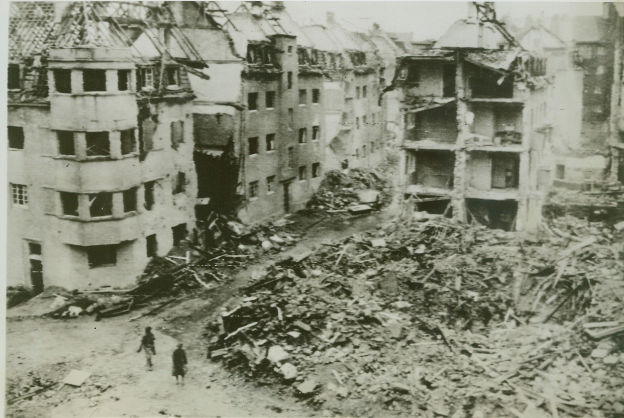 Path of Ruin into Aachen, 10/12/1944. GERMANY – This is a view of the ruined suburb of Aachen-Forst, which is approximately 150 yards from the city of Aachen, Germany. Crater at right and demolished houses are a sample of the fierce assault being directed at Aachen as American guns, planes and artillery begin systematic destruction of the city. Photo by Acme photographer, Andrew Lopez, for the War Picture Pool. Credit – WP- (ACME Photo via Army Radiotelephoto);