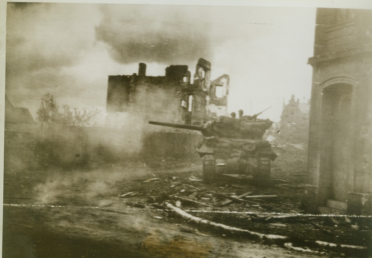 Guns of War Bark in Aachen, 10/15/1944. AACHEN, GERMANY – Battle smoke hangs low over the streets of Aachen as a tank destroyer sends a stream of fire toward the Germans. The barking war wagon is surrounded by buildings leveled by Allies bombardment after Nazi fighters refused to surrender. Credit (Acme Photo via Army Radiotelephoto);