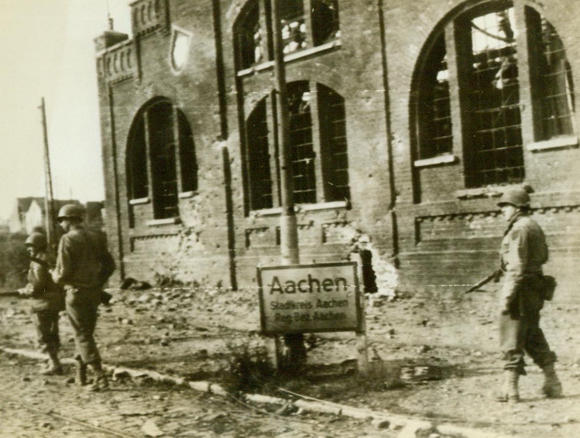 Alerted For Snipers In Aachen, 10/14/1944. Germany – An American infantry patrol walks cautiously ahead as it reaches the Aachen city limits rifles ready and alerted for enemy snipers. 10/14/44 (ACME);