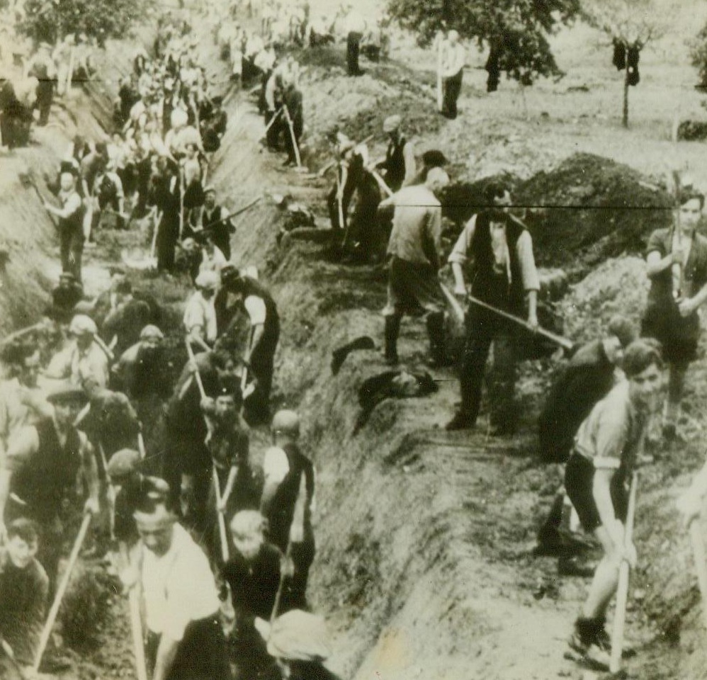 Traps For Allied Tanks, 10/16/1944. Moselle River Area, Germany – According to the caption accompanying this photo, radioed today from Stockholm, the picture shows a great gang, boys and men alike, of German civilians digging long tank traps in the Moselle River area. German caption states that it is “protection of “periphery” of Reich.” 10/16/44 (ACME);