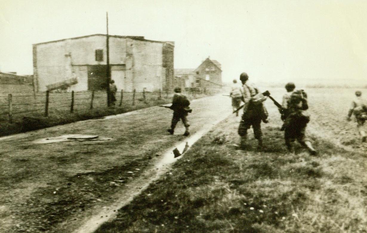 On Nazi "Holy Soil", 10/19/1944. With guns at the ready, American infantrymen cross a farm road beyond Kohlsheid, Germany, moving ever deeper into German territory and helping to close the trap on Aachen.  10/19/44 (ACME);