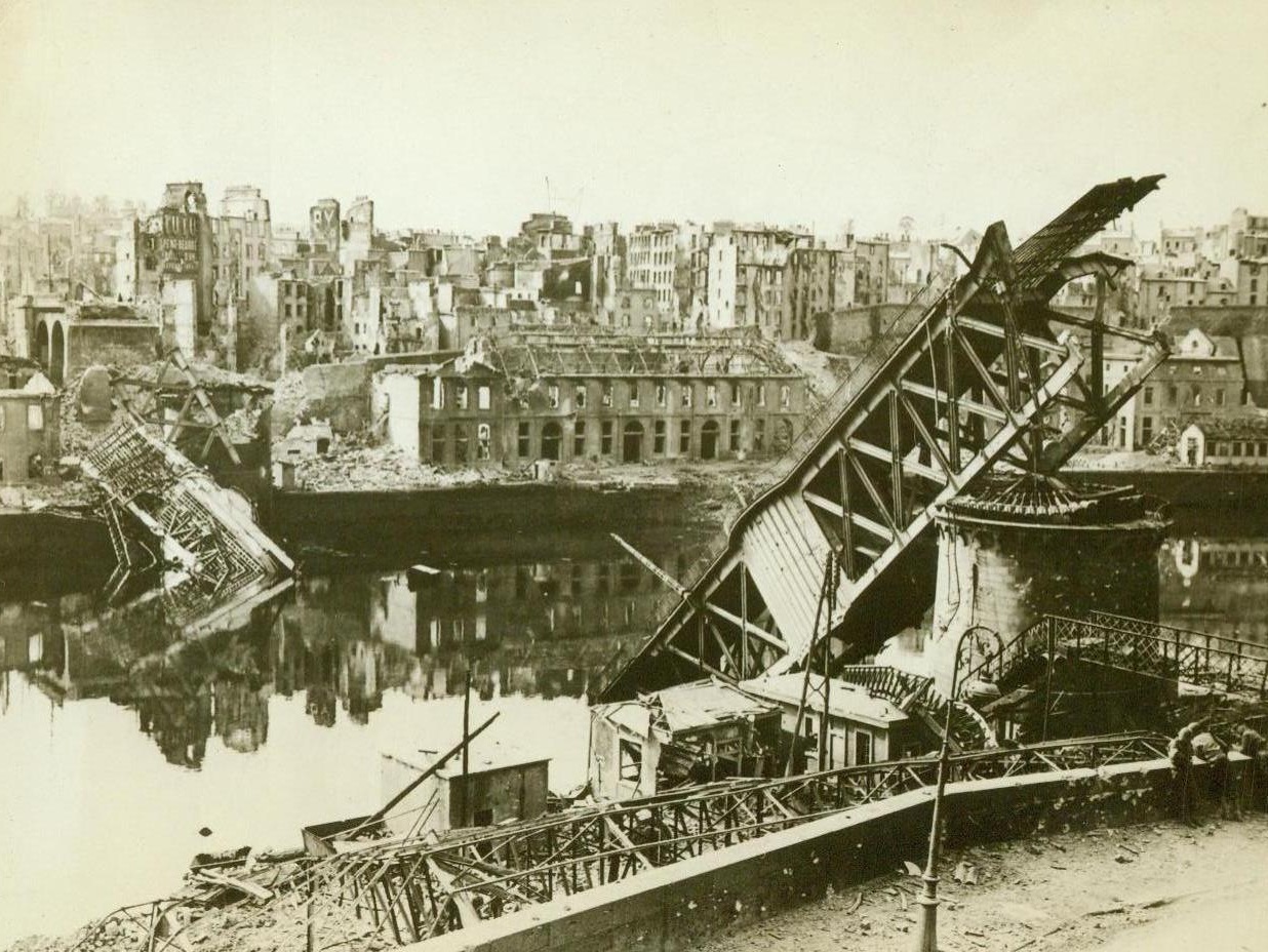 Shattered Brest Bridge, 10/9/1944. Brest, France – Broken in two, with each half tilting into the water, the Joan of Arc Bridge at Brest was hopelessly wrecked when the vital French city fell to the Allies. 10/9/44 (ACME);