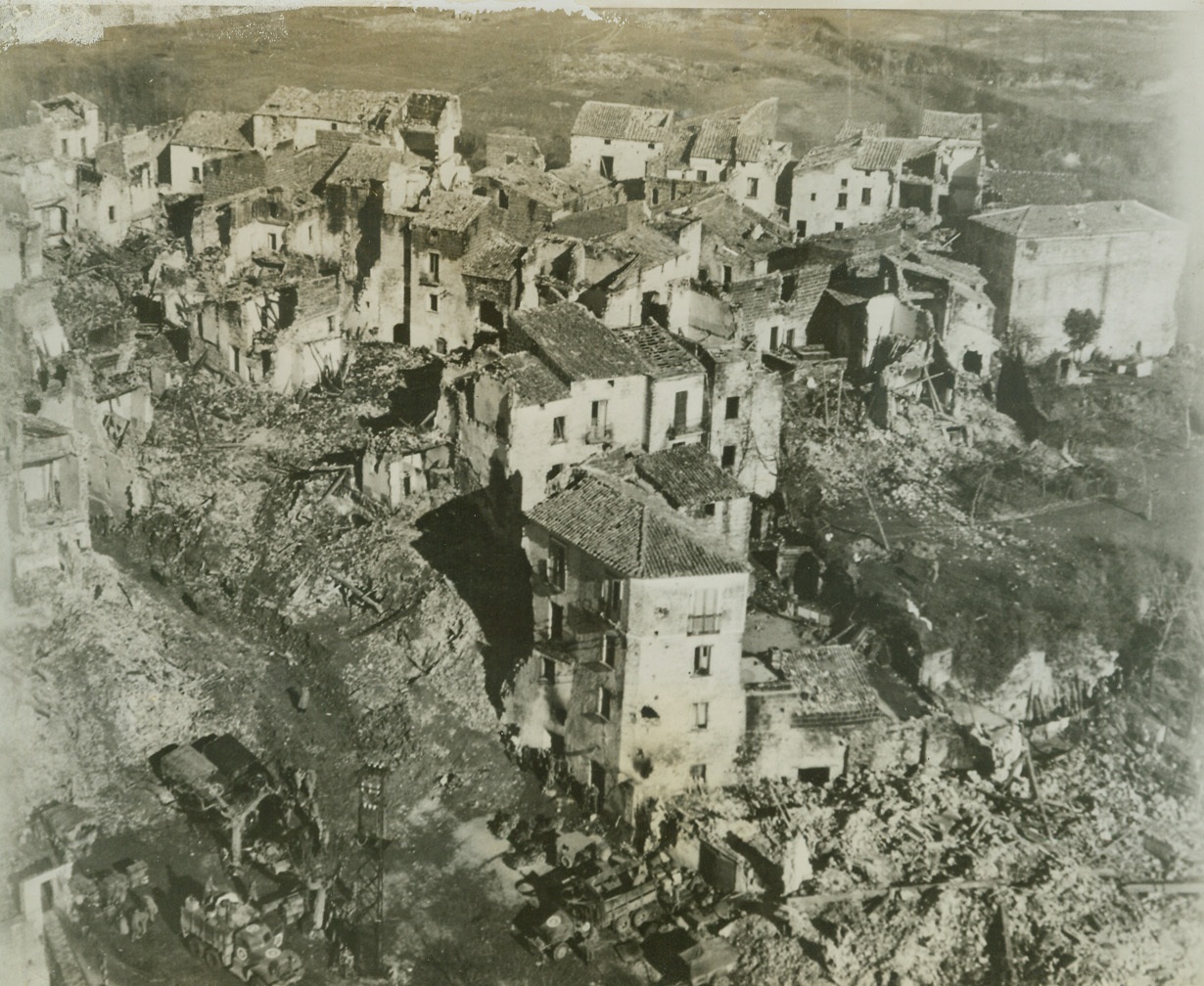In the Wake of War, 2/7/1944. Italy – Crippled by war, Mignano sags in the wake of the Allied charge on Messino. Fifth Army troops use the ghost town as an ambulance collecting point (foreground). Credit: (ACME);