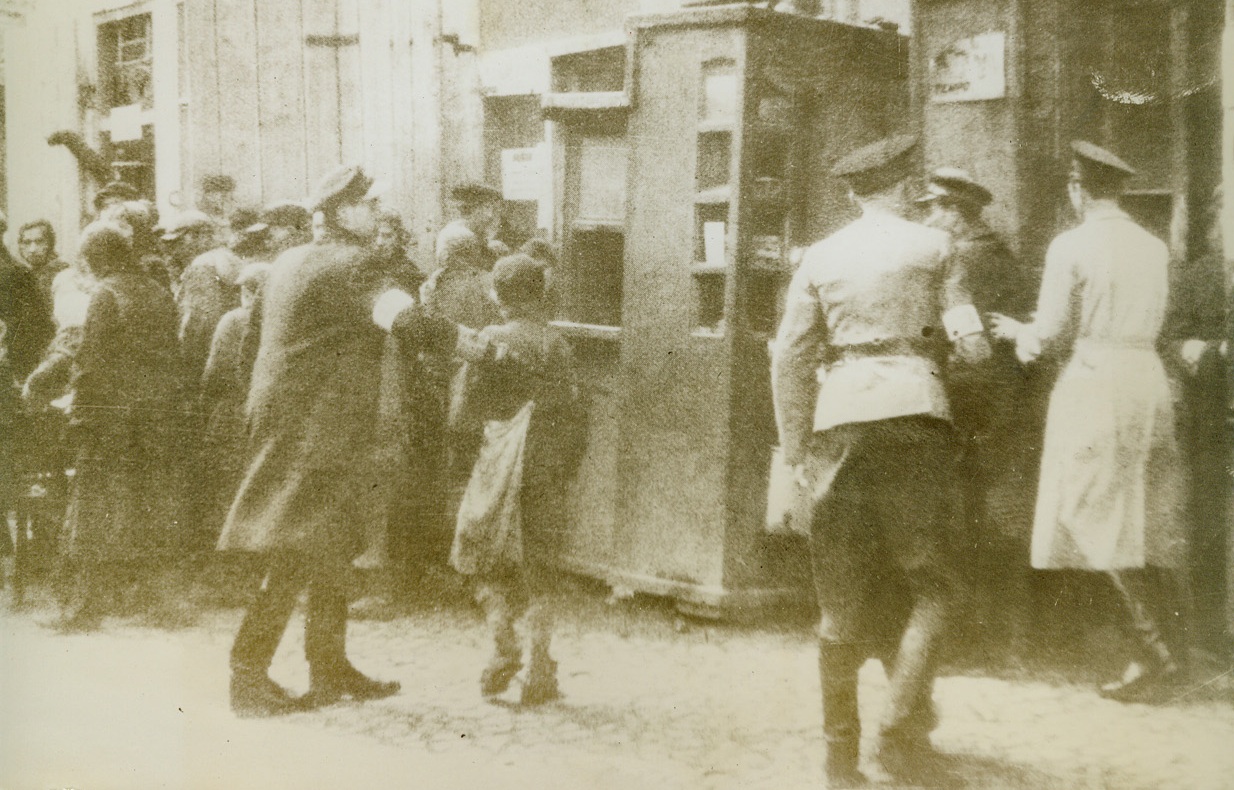 Watch Dogs Of The Ghetto, 2/1/1944. OCCUPIED EUROPE – Jewish police, operating in a ghetto market place, wear Star of David armbands and carry rubber truncheons. This photo, just received from a neutral source, is one of the first to show typical day-to-day scenes in a ghetto in German-occupied Europe where the Jews, separated from the rest of the population, carry on an entirely separate existence. Outside their walls, they are guarded by Gestapo police.Credit Line (ACME);