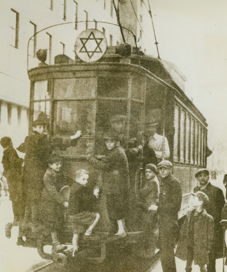 For Jews Only, 2/1/1944. OCCUPIED EUROPE—Crowded to capacity, with Jewish children clinging to the outside, a ghetto street car starts off on a journey, the Star of David (top of car) prominently displayed. The public conveyance is confined to the limits of a ghetto, somewhere in German-occupied Europe, where Jewish people are packed together and segregated from the rest of the world.Credit: Acme;