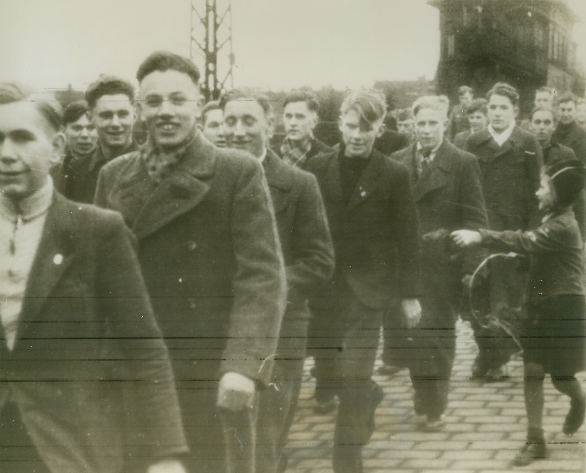 More Fodder for Hitler’s Cannons, 2/2/1944. Germany—Volunteers for Germany’s so-called armoured infantry division “Gross Deutschland,” many of whom are obviously only 15 years old, stage their first “parade” through the town where the division is stationed before they have even received their uniforms. Seemingly unaware of the grim death that awaits most of these unseasoned fighters, a little girl (right) happily offers a parting gift to one of the “men.” Photo radioed from Stockholm this morning. Credit: ACME radiophoto.;