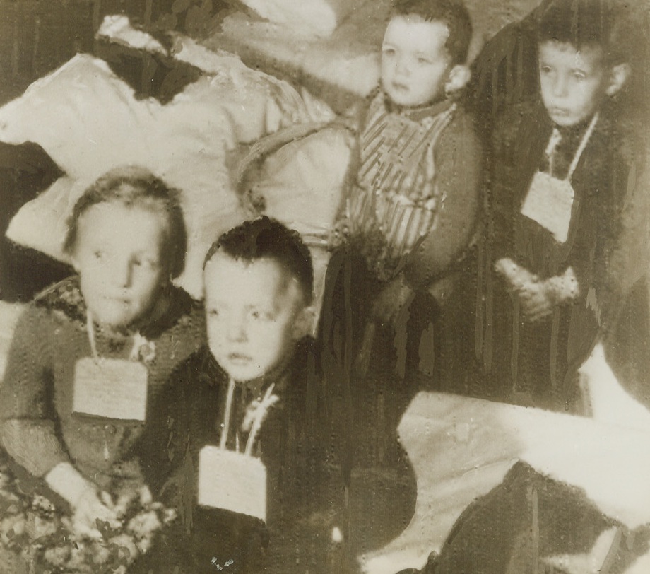 YOUTHFUL REFUGEES, 2/15/1944. STOCKHOLM, SWEDEN—Tired and bewildered, four Finnish youngsters sit quietly with hands folded and tags hung around their necks for identification purposes. The children, evacuated from embattled Finland, are shown as they arrived in Stockholm. Photo radioed to New York today (Feb. 15th). Credit: Acme Radiophoto;