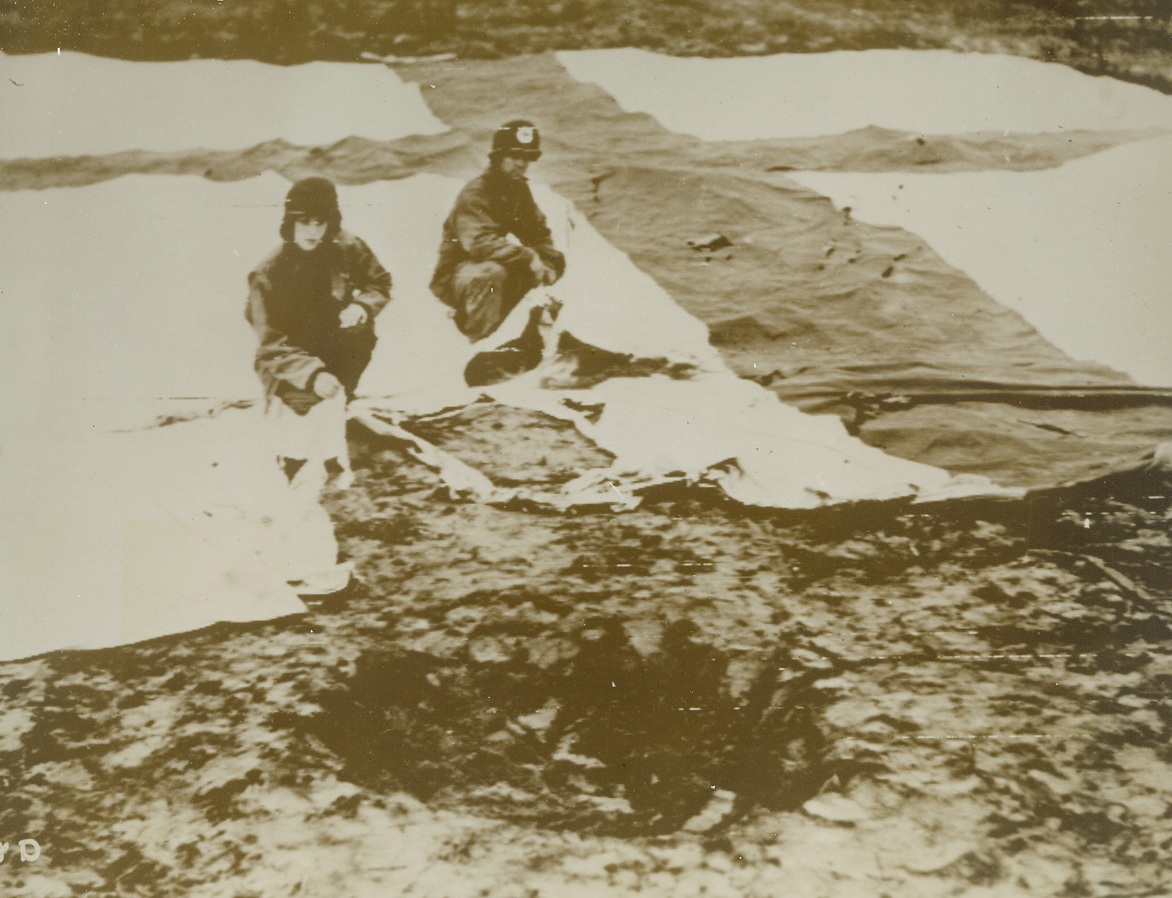 After German Bomber Passed, 2/12/1944. ITALY -- Nazi anti-personnel bombs ripped that American Red Cross flag which is spread out behind the bomb crater on the grounds of an evacuation hospital near the Nettuno beachhead. Nurse Lt. Sally Hocutt, of Wendell, N.C. (left) and Pvt. Marshall Floyd, of Marshville, N.C., view the damage to the tent hospital, blasted by the enemy. Credit (ACME Photo via U.S. Army Signal Corps Radiotelephoto);