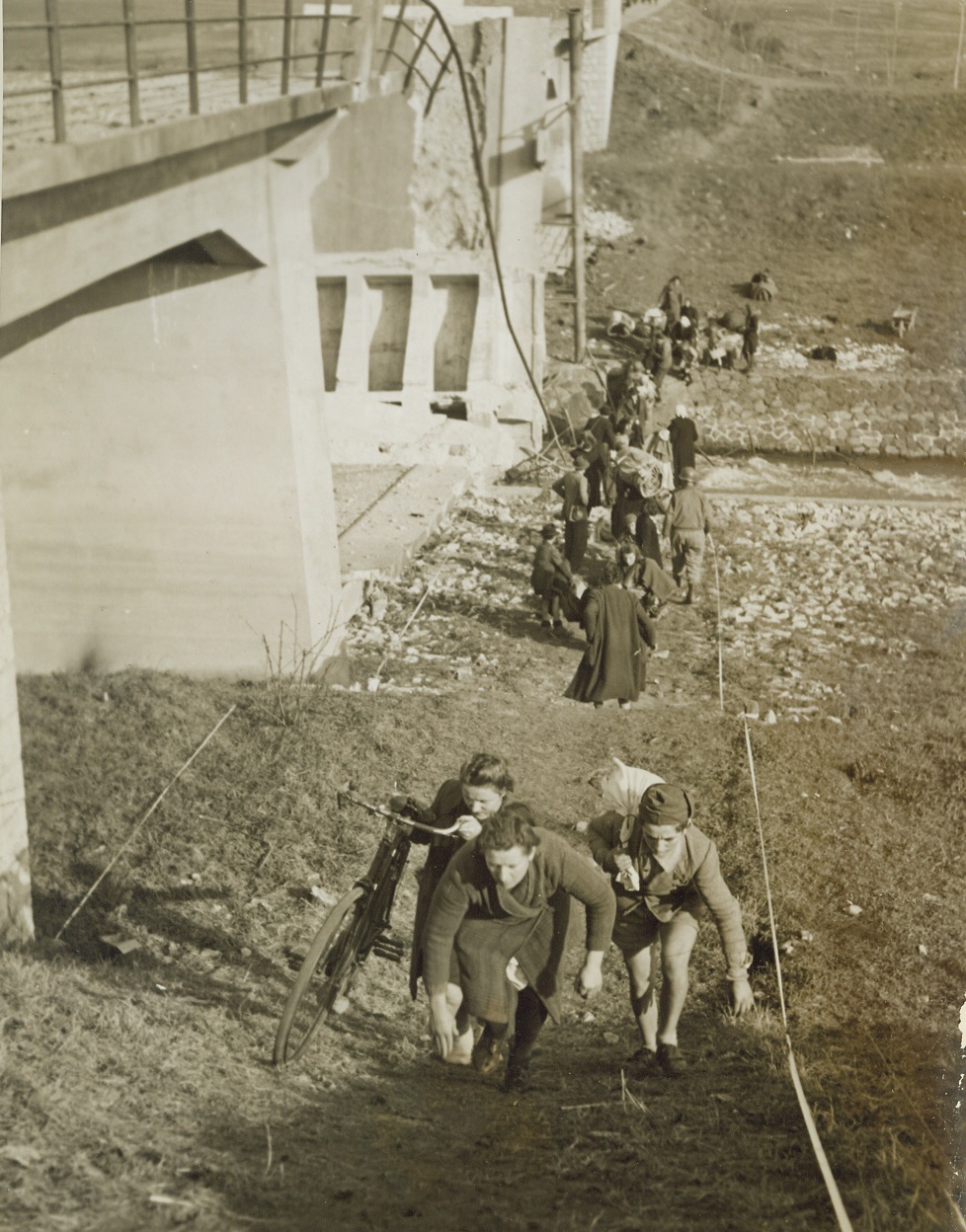 No "Double-Cross" For the Mussolini, 2/11/1944. ITALY -- These Italian refugees are permitted to cross the Mussolini canal, but only in one direction -- toward Allied territory. American soldiers help the natives across the small waterway where retreating Germans blasted a concrete bridge. Credit (Acme Photo by Charles Seawood, War Pool Correspondent);