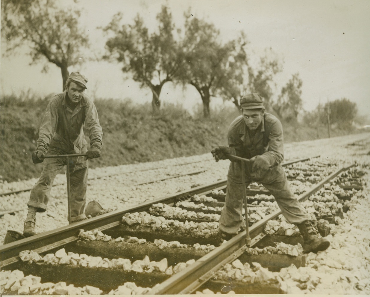 “I’m Working on the Railroad”, 2/9/1944. SOUTHERN ITALY – Corp. Tech. Robert B. Force, of Springfield, Ill., left, and Sergt. Tech. Fritz Herzog, of Shidmon, Tex., repair the damage done to Italian railroads by the retreating Germans, and by Allied shelling and bombing before the area was captured.Credit (ACME);