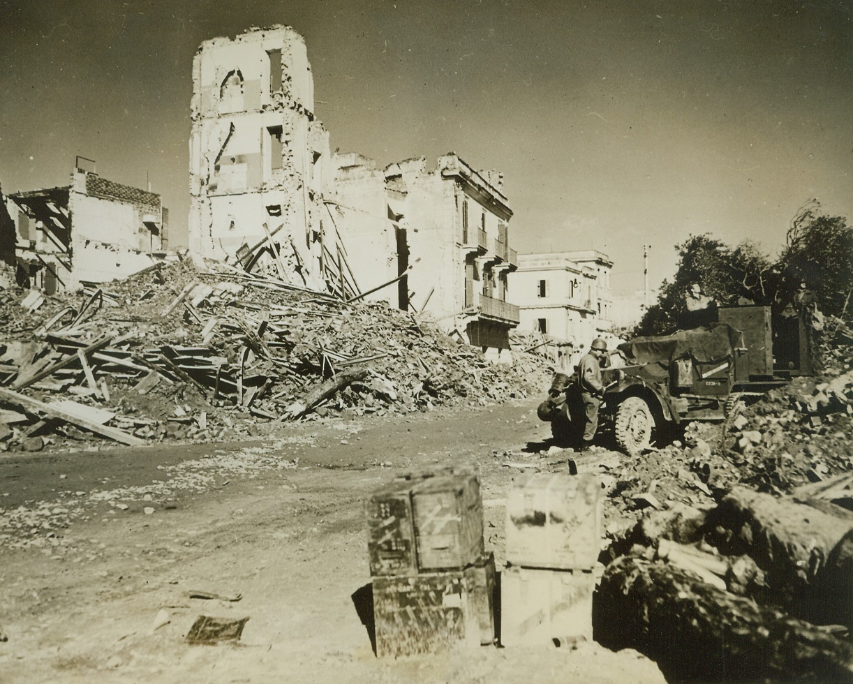 After War Passed Through Anzio, 2/17/1944. ANZIO, ITALY – These shattered buildings at Anzio, through which men and supplies are streaming toward the Allied 5th Army front below Rome, bear the grim mark of battle. At right, an American half-track protects the road from German air attacks. Today, the Allies are fighting bitterly to stem Nazi counter-attacks in the Anzio-Nettuno sector, and are throwing back each one with terrific losses to the enemy.Credit Line (U.S. Navy Photo from Acme);