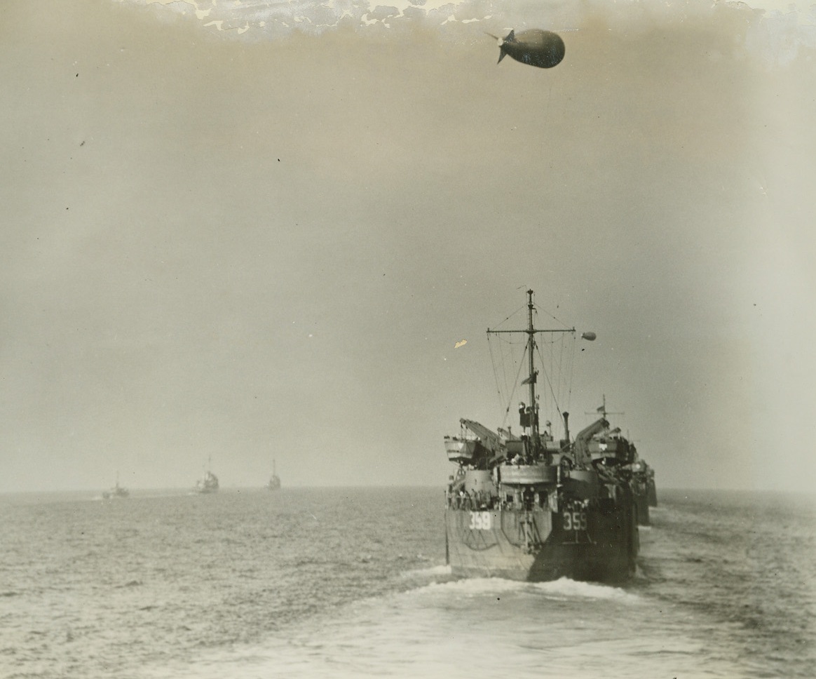 HEADED FOR DRIVE ON ROME, 2/3/1944. This photo, one of the first originals to reach the United States, was taken as the massive Allied invasion fleet headed toward beachheads in the vicinity of Nettuno and Anzio for the drive on Rome. At right, (above) is a LST (Landing Ship, Tanks) with its barrage balloon hovering above. In left, background, are LCIs (Landing Craft, Infantry). Today it was announced that American Infantry, supported by tanks, had driven into the northwestern part of Cassino.  Credit Line (ACME Photo by Bert Brandt for the War Picture Pool);