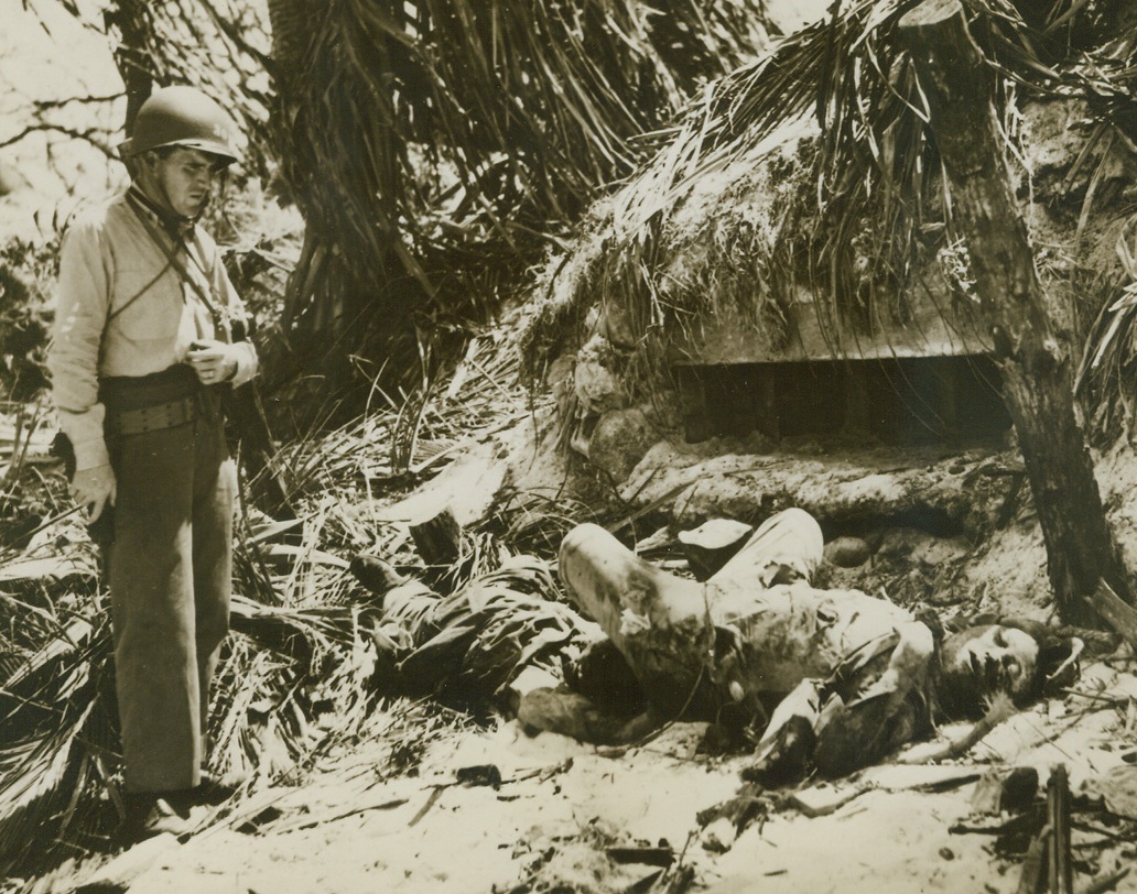 To Their Ancestors, 2/19/1944. Kwajalein Atoll – Coast Guard Ensign Robert C. Preston of New London, Conn., stops to look at the bodies of two Japanese imperial Marines on Kwajalein Atoll in the Marshalls.  The enemy fighters lie stiffly before their silenced pillbox in which 23 more dead Japs were found.Credit Line (U.S. Coast Guard photo from ACME);