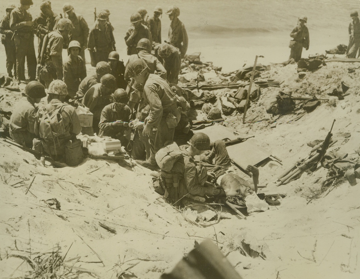 New Strength For The Wounded, 2/28/1944. Eniwetok Atoll – Medical corpsmen give blood transfusions to the Marines who were wounded wresting Eniwetok island from veteran Japanese fighters.  In the foreground, a Leatherneck receives plasma while in the background other corpsmen get supplies to be rushed to nearby wounded.Credit (Official Coast Guard photo from ACME);