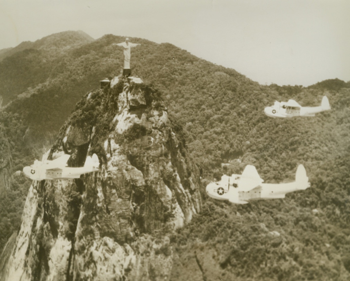 The Eternal--and the Modern, 2/1/1944. Rio de Janeiro -- As though casting a blessing over these three white, gull-like Martin Mariners of the U.S. Navy, this statue of Christos Redemptor--Christ, the Redeemer--stands with outstretched arms atop Corcovado Peak near Rio de Janeiro. The war planes are part of a group flying on Navy Business, guarding convoys to and from Brazil. Credit: U.S. Navy photo from ACME;