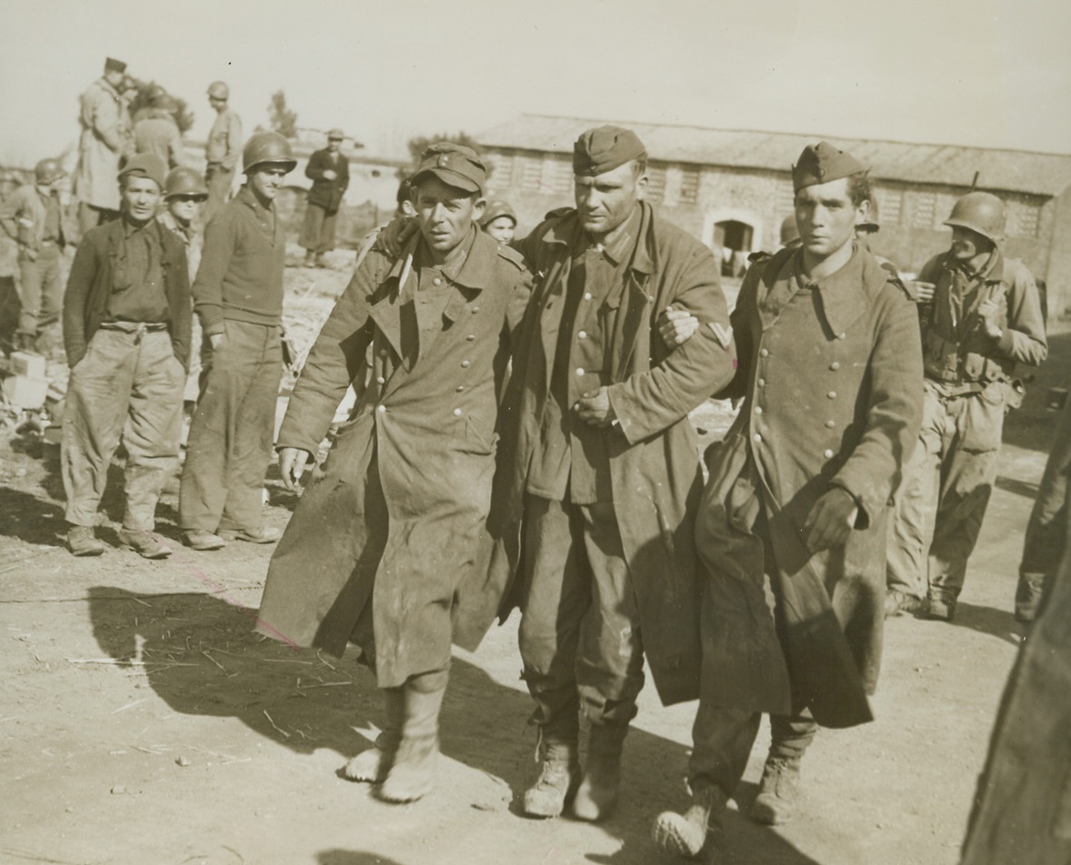 Helping Wounded Captive, 3/3/1944. CARROCETA, ITALY—A pair of angry-looking Nazi captives help a wounded buddy along as they are led to a prisoner of war cage behind Allied lines in Italy. Surrounded by an armored division thrust during the fighting new Carroceta, the Germans surrendered to Fifth Army infantrymen. Credit: ACME PHOTO BY SHERMAN MONTROSE FOR THE WAR PICTURE POOL.;