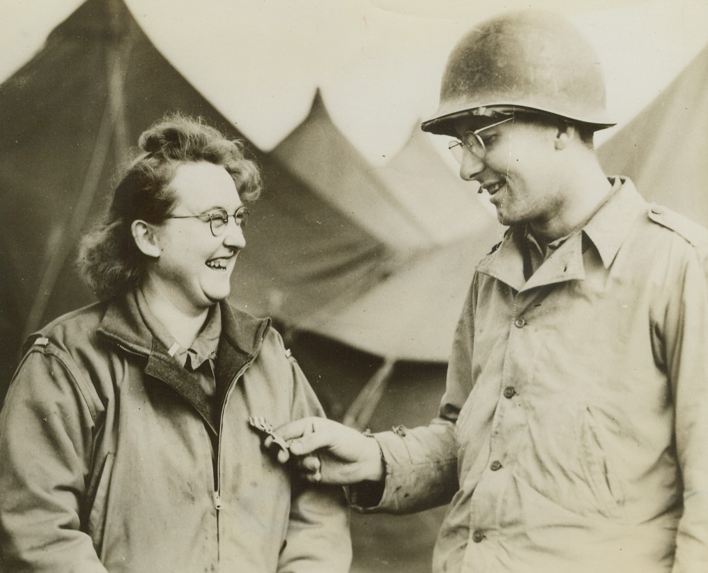 HEROINE OF THE BEACHHEAD, 3/8/1944.ITALY—Cpl. Richard Nordwall, Rockford, Ill., is admiring the Silver Star of Lt. Elaine A. Roe, U.S. Army nurse who won the decoration on the Anzio-Nettuno beachhead for her gallantry in action when Germans shelled field hospital to which she was attached last month. Lt. Roe helped carry out evacuation of 42 patients during the shelling. Lt. Roe is from White Water, Wisc. Credit: Acme;