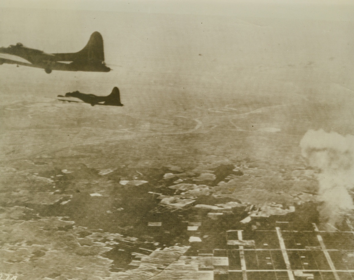 Among Those Missing, 3/10/1944. GERMANY – A shattered Flying Fortress wears a shroud of smoke (right) after a direct hit from flak over a Berlin suburb. Sister ships roar on, during the daylight raid of March 6th.Credit (U.S. Army Air Forces Photo via Radiotelephoto from Acme);