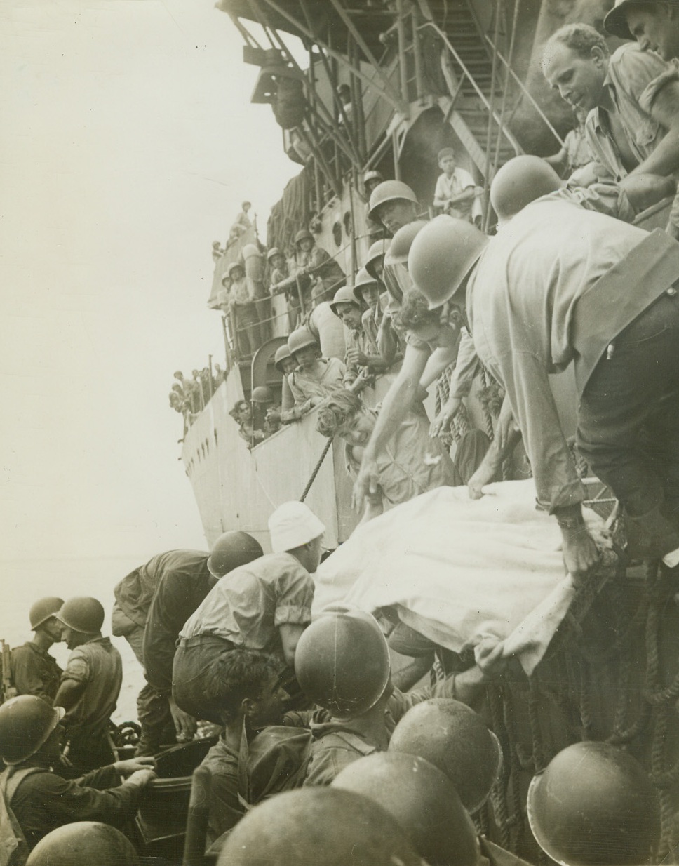 Los Negros Casualty Brought Aboard Destroyer, 3/14/1944. Los Negros Island, - Wounded in first moments of action after storming Los Negros island.  This soldier is lifted aboard destroyer for medical aid.  Photo by Frank Prist, Jr., ACME photographer for War Pool. Credit line ACME;