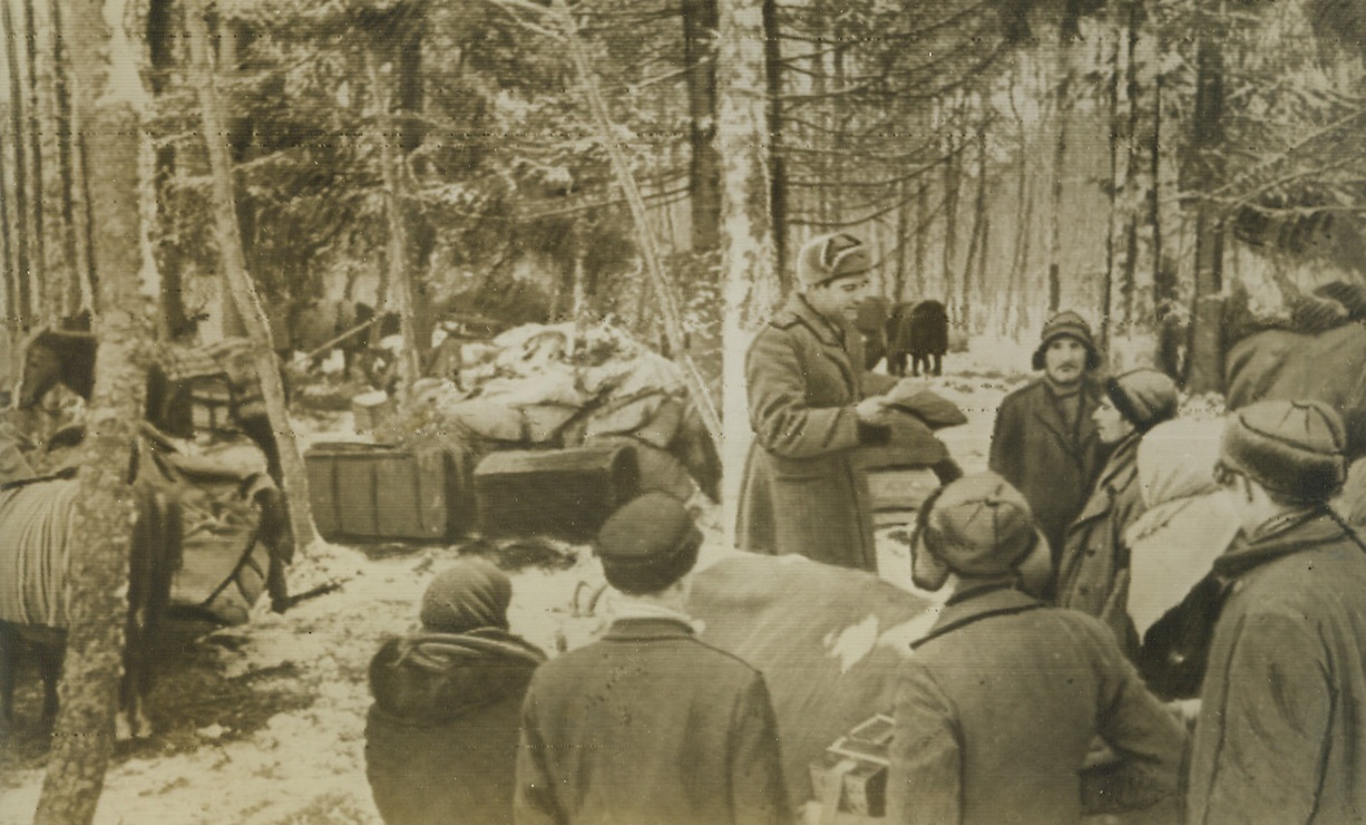 Advancing Reds Meet Forest Dwellers, 3/5/1944. Estonia—Estonians, who took to the wild forests of their country to hide from the Germans, gather around an officer of the Soviet forces now attacking southeast of Vitebsk, near Pskov and Narva. Fighting is fierce for Pskov, the Baltic gateway city almost on the borderline of Russia and Estonia, with the Germans trying to stem the Red Tide along an intricate network of “hedgehog” defenses. Credit: ACME radiophoto;