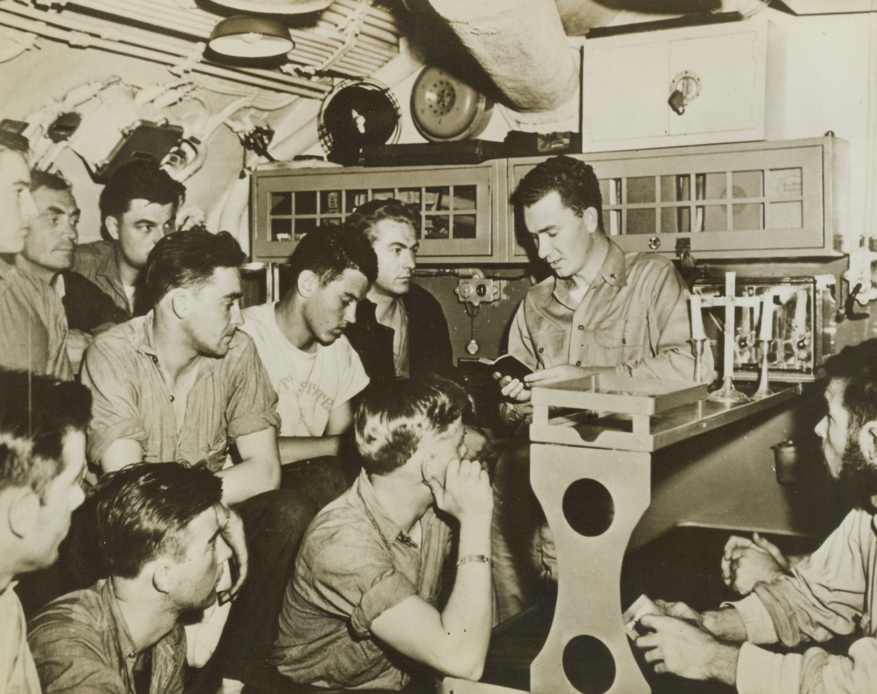 UNDERSEAS SERVICE, 3/28/1944. “SOMEWHERE AT SEA” : With a simple cross placed on a mess counter, Chaplain W.S. Brown, of Toledo, O., holds a church service in the confines of a U.S. submarine while it’s out on sea war patrol.  It was believed to be the first service of its kind, as underseas fighters do not usually carry Chaplains.  Chaplain Brown was a passenger aboard the submarine on his way to a new station “somewhere in the Pacific.”Credit: Acme;