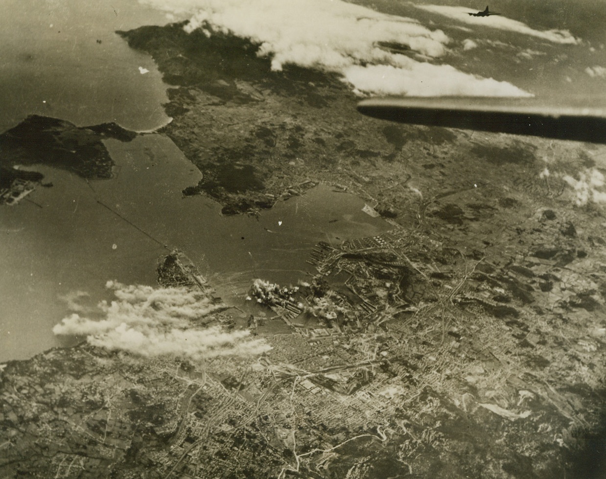 BLASTING SUB PENS AT TOULON, 3/8/1944. This photo, released in Washington today, shows bombs exploding on Nazi-held submarine pens (exact center of photo) in the harbor at Toulon, France, was taken by Major Gordon Sarre, of New York City, during a recent raid by heavy bombers of the U.S. Army Air Forces.  To the left of the exploding bombs (in photo) columns of smoke mark burning installations. Today, it was announced that heavy U.S. bombers had again blasted Toulon. Credit: USAAF photo from Acme;