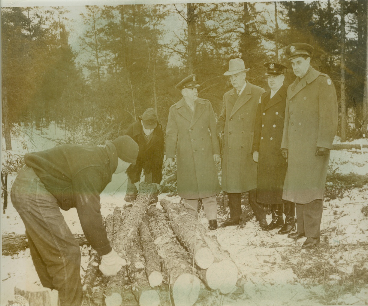 NAZIS HELP OUT IN NORTH WOODS, 3/12/1944. CAMP EVELYN, MICH. – Several hundred German prisoners from Rommel’s Afrika Korps have been brought to two former CCC camps in Northern Michigan near Evelyn and Sadinaw where they will learn the use of the double-bitted Michigan ax and the two-man saw with which they will cut pulp and chemical wood in this critical manpower shortage area. Geneva Conference provisions forbid prisoner of war participation in hazardous work, so these men will engage in less dangerous, but still necessary operations. Col. W.H. McCarty, Gov. H.F. Kelly, Michigan Police Commissioner Oscar G. Olander and Col. S.D. Ringsdorf (left to right) inspect logs cut by prisoners of war at Camp Evelyn, Mich. Credit: U.S. Army photo via OWI Radiophoto from ACME;