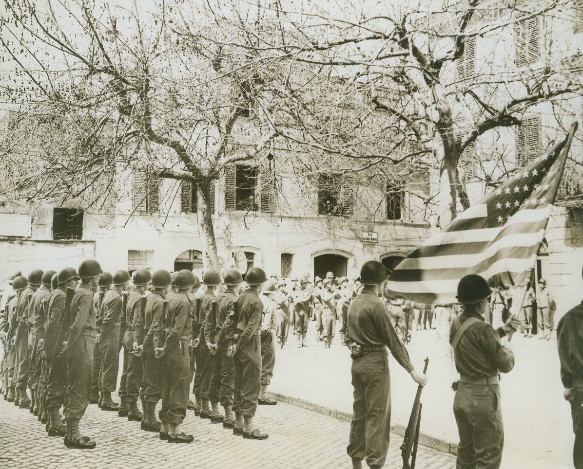 Old Glory and Awards in Sunny Italy, 4/14/1944. Nettuno, Italy—Old Sol paid his respects and sunny Italy lived up to her name as Old Glory was unfurled at ceremonies for the presentation of Silver Star Medals to soldier heroes of the fighting in the beachhead area around Nettuno, Italy. Credit: ACME.;