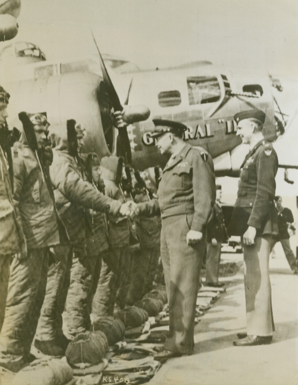 Greets Crew of His Namesake Plane, 4/13/1944. Gen. Dwight Eisenhower, has a grin and a handshake for the crew of "General Ike", newest model B-17 G Silver Flying Fortress, as he christens the ship during an inspection tour of the base. This latest B-17 is unpainted, and thus gains in speed due to less weight and friction loss. To the right of Gen. Eisenhower is Col. Claude E. Putnam, Jacksboro, Texas, group Commanding Officer. Credit (US Army Radiotelephoto from ACME);
