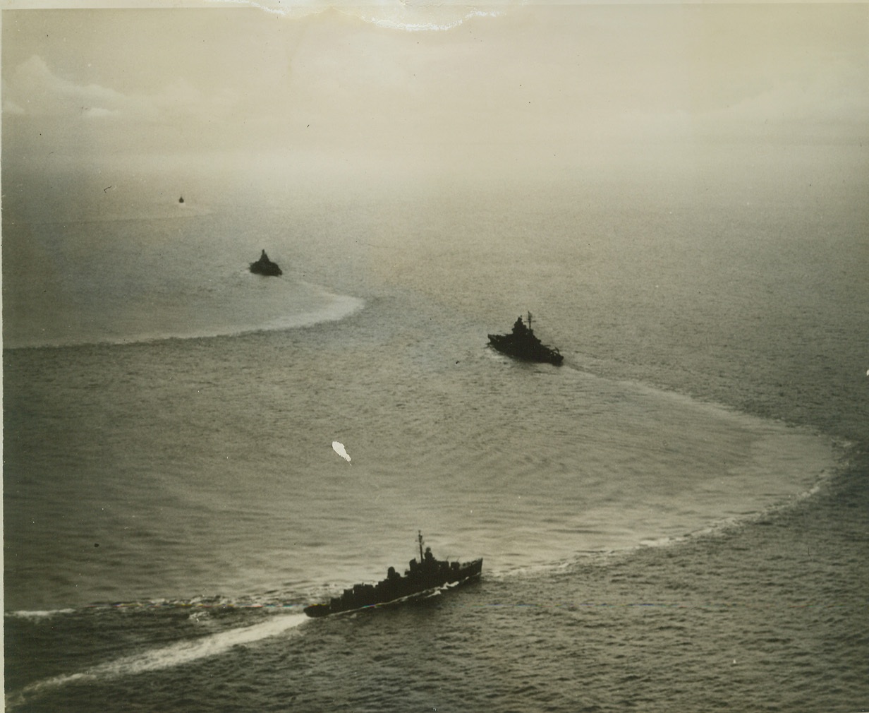 Yank "Triphibian" Attack, 4/24/1944. This photo, just released in the U.S., shows four American warships executing a maneuver to port forming a battle column in which the vessels' maximum fire power may be brought to bear of Jap installations at Kavieng, New Ireland. This was part of the "triphibian" attack by land, sea, and air on Kavieng, and at Emirau in the St. Matthias Islands, last March 19. While fleet units blasted Kavieng as a feint, Marines landed at Emirau. Credit: ( U.S. Navy Photo from ACME);