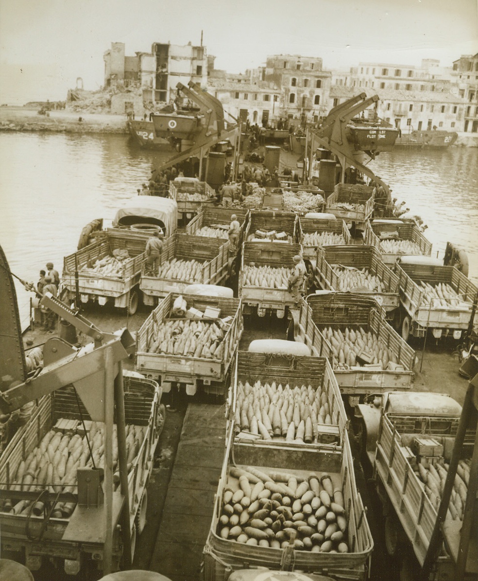 Shells for Guns in Italy, 4/22/1944. ANZIO, ITALY – Hitler’s troops at the Italian front are to be the eventual recipients of this “present” for our fighting men in Italy. An American LST is shown approaching Anzio harbor with trucks loaded with shells to provider “gun fodder” for Fifth Army guns on the Anzio front. Credit Line (Acme);