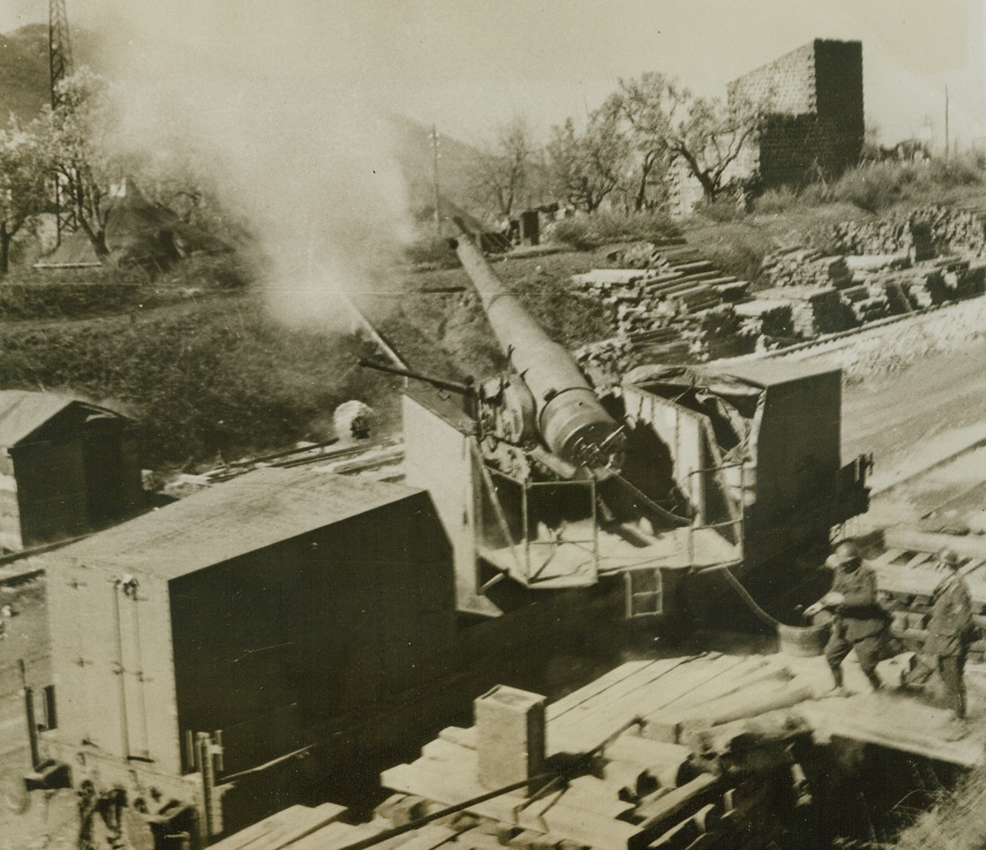 Railway Guns Blast Nazi Strongholds, 4/18/1944. Cassino Front, Italy – Firing over a range of 10 miles, the first railway guns went into action against the Germans on the Fifth Army Front. The three big guns belong to a Battery of an Armored Regiment of the Italian Army, and were manned by Italian soldiers. German strongholds received blast after blast from these big 194mm caliber weapons. Credit: ACME;