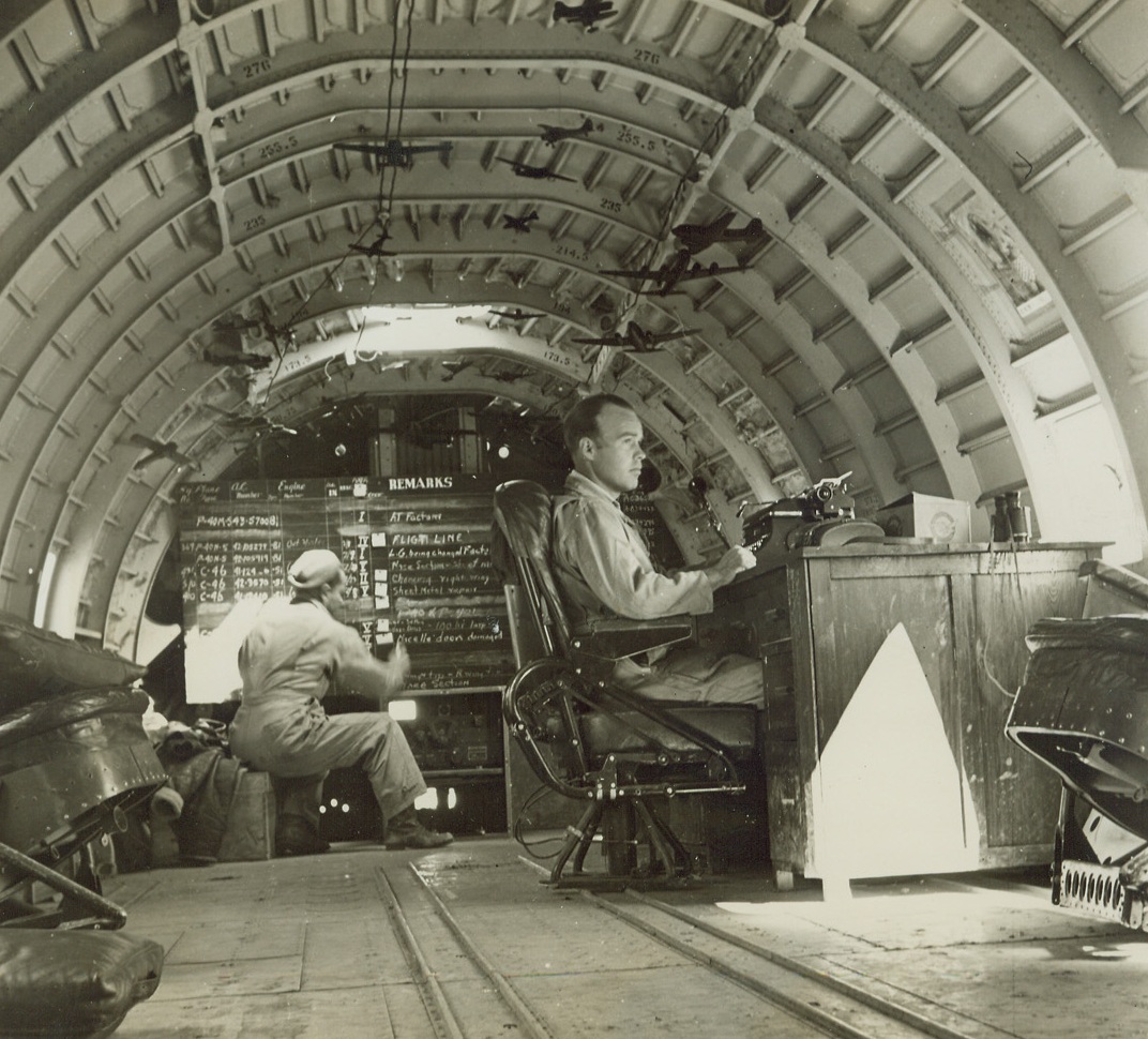 This Office Came From the Skies, 4/10/1944. An Air Base somewhere in China – Interior of cracked up transport is used as an office and alert shack. Operating the operations board is Sgt. Willard Mitchell, Portland Oregon. Sgt. Wm. Casto, Anaconda, Montana, is at the desk. Credit: ACME photo by Frank Cancellare, War Pool Correspondent;