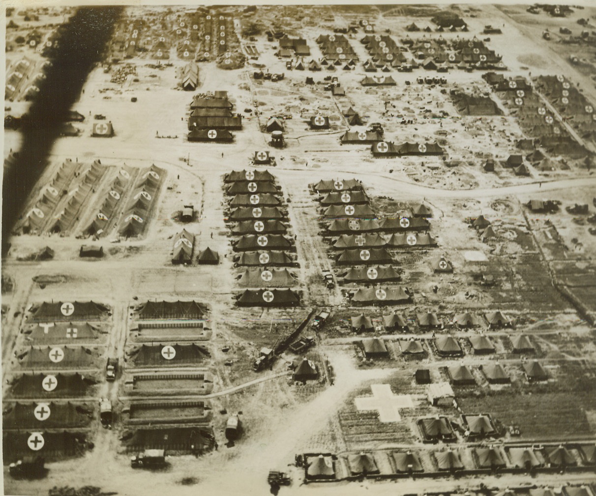 "Cold Turkey" for Nazis, 4/19/1944. ANZIO, ITALY -- Here's how this evacuation hospital looked to German fliers who bombed it recently, killing many wounded and members of the staff. The Red Crosses on the tents and the huge ones on the ground stand out clearly and could not possibly have been mistaken by Nazi raiders. At the left (in photo) bomb craters from the air attack can still be seen, although most have the damage to tents and buildings had been repaired, when this photo was taken from an Allied observation plane. Credit: (ACME) (WP);