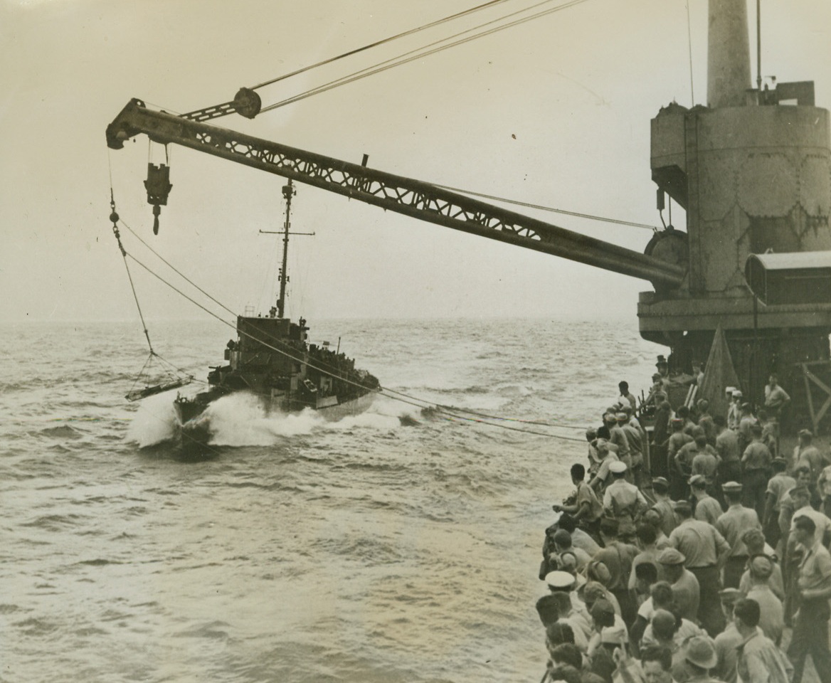Water Ambulance, 4/17/1944. At Sea – While the patient, destined for an emergency appendectomy, swings from the crane of a seaplane tender in the South Pacific, a destroyer escort plows ahead to pick him up for further transfer to a base hospital.  Men on the tender watch the transfer with anxious eyes.Credit Line (Official US Navy photo from ACME);