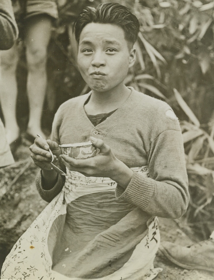 Rising Sun’s His Apron, 4/7/1944. Burma—Swallowing a mouthful of rice, which he’s eating with a spoon instead of chopsticks, this Chinese warrior uses a captured rising sun flag for an apron.  He’s already dropped a few grains of the food on the “sun”.  The allied fighter is one of the transport boys attached to 75 mm guns manned by Gen. Joe Stilwell’s men. Credit line –WP- (ACME;