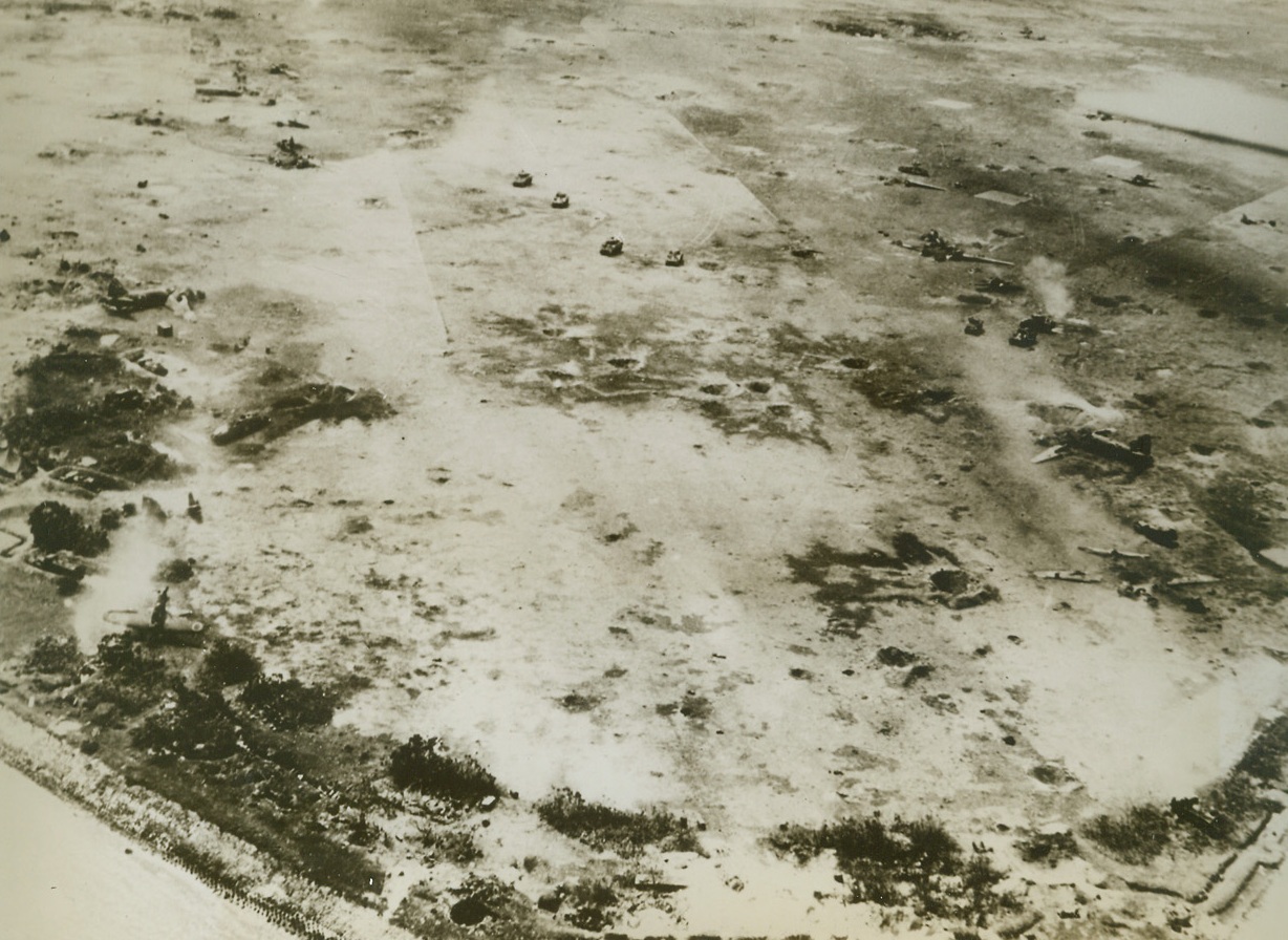 Panorama of Battle to Death, 4/5/1944. Kwajalein – in this unusual battle picture taken by U.S. Navy planes, a small band of Japs (entrenched in the semi-circle in foreground) puts up the last-stand fight for Kwajalein against U.S. tanks advancing across the wrecked Nip airfield (top of photo).  Scattered about the field (right) are the gaunt skeletons of shattered Jap planes.  Photo was taken above the Marshall Island Atoll last Feb. 2nd and released in the U.S. Today. Credit line (U.S. Navy official photo from ACME);
