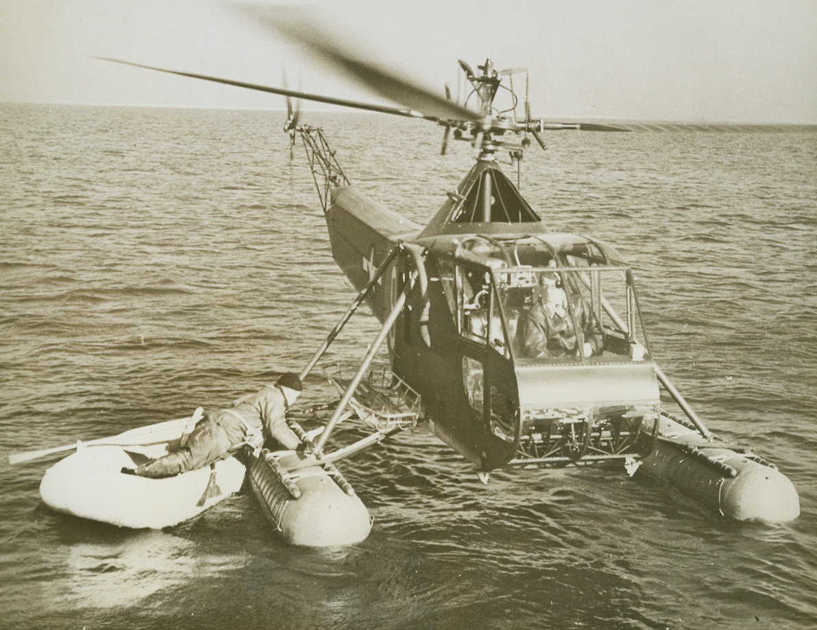Helicopters to the Rescue #1, 4/16/1944. New York City—The Third Naval District’s air arm of the U.S. Coast Guard is now using helicopters for patrol and rescue assignments. While such uses are admittedly in experimental stages, Coast Guardsmen have found that, particularly in the case of rescue work, the little plane is speedier and eliminates much of the rough handling unavoidable in other methods of rescue. In a recent demonstration, the helicopter (above) settles on the water next to a “wounded” flier on a life raft and rests on pontoons while the injured man climbs aboard to the stretcher basket.Credit: Coast Guard photo from ACME.;
