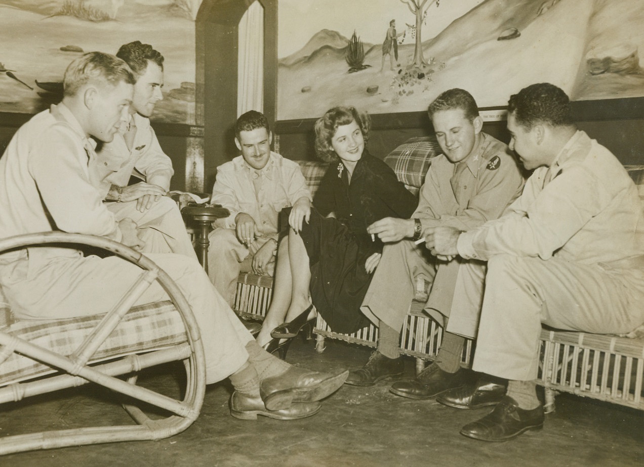 Rest Haven In Hawaii, 4/25/1944. Hawaii – The pretty Army hostess, Miss Beatrix Eklund, of Hilo, Hawaii, has her hands full entertaining five officers at once, but she seems to have the situation well in hand. The group of officers (left to right): 1/Lt. Roscoe White, Shreveport, La.; William W. Pittendreich, New Bedford, Mass.; Lt. John Wattich, Library, Pa.; and Capt. M.M Weinstein, Stamford, Conn., Are at the Kilauea Military Camp taking a rest after active duty in the combat area of the Pacific. 4/25/44 Credit (ACME);