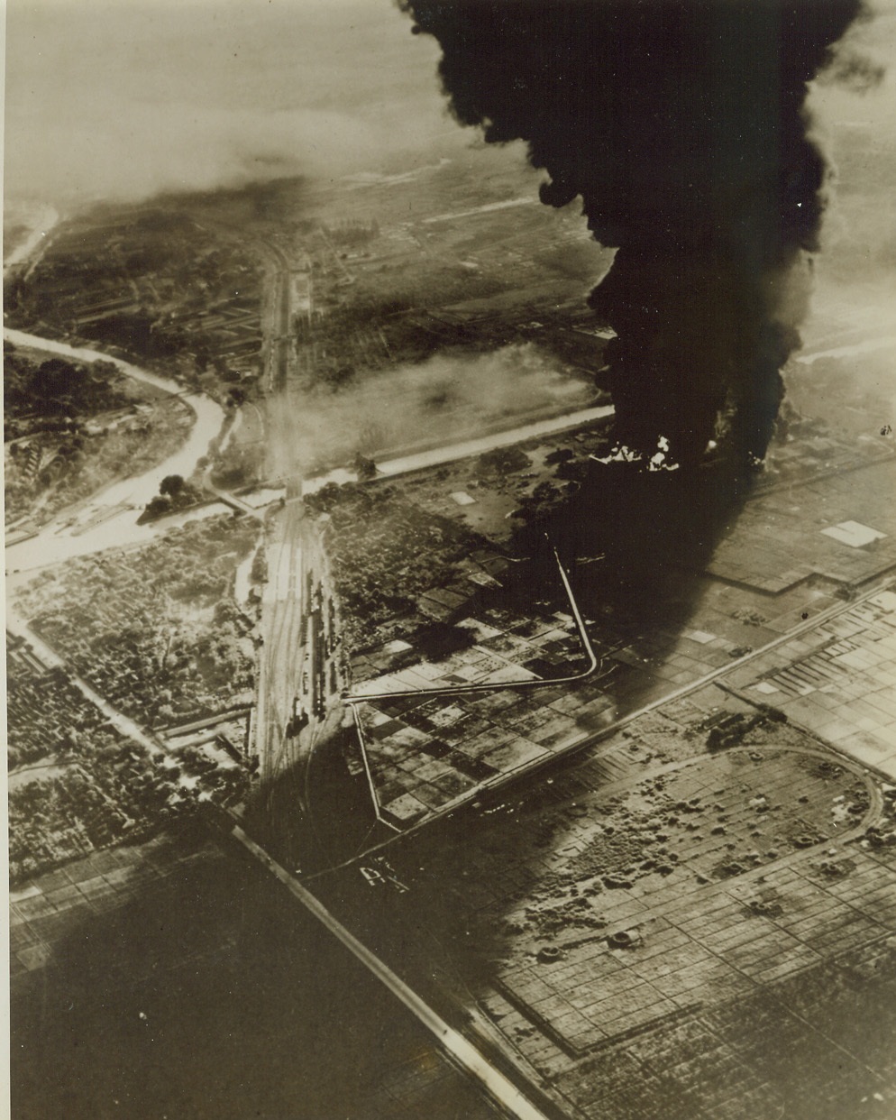 JAP FUEL BURNS AT SOERABAYA, 5/30/1944. SOERABAYA, JAVA – A huge shadow is cast across the country-side as jet black smoke rises from a fuel fire started by Allied raid and obscures the sun. This was part of the wide damage done to Jap installations at Soerabaya during recent large scale attack on that Jap-held city in Java, Netherlands Indies. Credit: Official U.S. Navy photo from ACME;