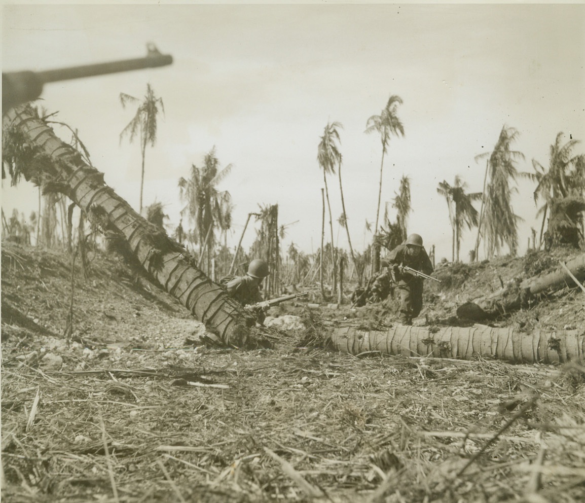 CAUTIOUS ADVANCE, 5/31/1944. WADKE ISLAND – With a medium tank providing cover for their advance, these American infantrymen, members of the U.S. invasion force that seized Jap-held Wadke Island, Dutch New Guinea, move cautiously forward as they search for Jap snipers. Gun of tank is visible at upper left. Credit: ACME photo by Frank Prist, War Pool correspondent;